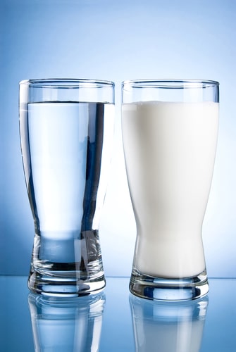 A glass of water next to a glass of milk.